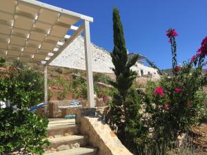 a white pergola with stairs in a garden with flowers at HydraVista (Coral) in Hydra