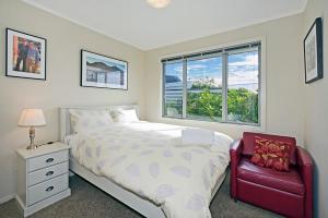 a bedroom with a bed and a red chair at Above The Cut in Nelson