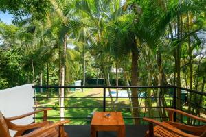 a balcony with two chairs and a table and palm trees at Chandra Villa Ayurveda Resort in Bentota