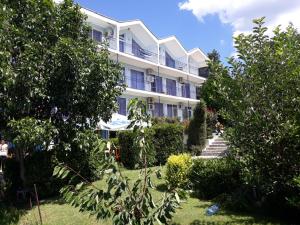 a large white building with trees in front of it at Вила Синя Иглика in Kosharitsa