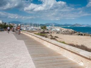 a boardwalk on a beach with people walking and the ocean at Fantastic, 100 meters from the beach in Can Picafort