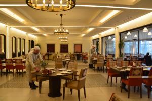 dos personas de pie en el comedor de un restaurante en Saray Hotel Amman en Amán