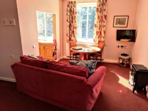 a living room with a red couch and a table at Mellwaters Barn Cottages in Bowes