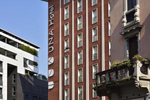 a red brick building with a balcony in front of it at UNA Hotels Mediterraneo Milano in Milan