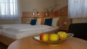 a hotel room with a bed and a bowl of apples on a table at Hotel & Restaurant Karpfen in Illmensee