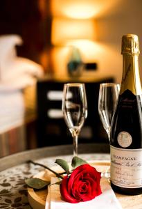 a bottle of wine and a rose next to a glass at Baraset Barn Hotel in Stratford-upon-Avon