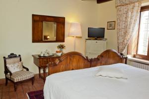 - une chambre avec un lit, une chaise et une télévision dans l'établissement Azienda Agrituristica Corteforte, à Fumane