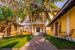 a yellow building with palm trees in front of it at Fiesta Beach Resort in Baga