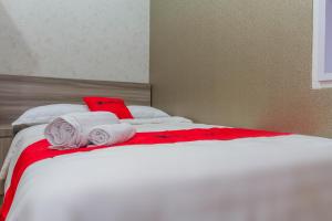 a white bed with red sheets and towels on it at RedDoorz Plus near IPDN in Sumedang