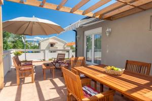 a wooden table with chairs and an umbrella on a patio at Apartments Kukuriku in Baška