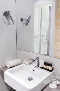 a white bathroom with a sink and a mirror at Hôtel La Cour Carrée Bordeaux Centre in Bordeaux