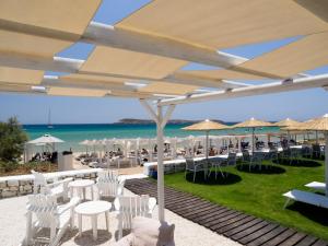 un restaurante con sillas blancas y sombrillas en la playa en Amaryllis Beach Hotel en Chrissi Akti
