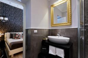 baño con lavabo, espejo y cama en Sistina Twentythree luxury rooms, en Roma