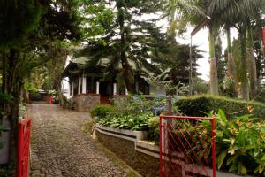 OYO 604 Cemara's Homestay في باتو: حديقة فيها بوابة حمراء وبعض النباتات