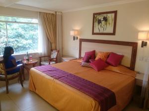 una habitación de hotel con una cama y una mujer sentada en una mesa en Hotel Riverview Westlands, en Nairobi