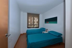 a room with two blue beds and a window at Apartamento CERCA PLAYA CON BALCON Y BBQ in Calafell