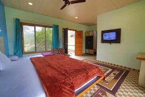 a bedroom with a large bed with a flat screen tv at Aditya Forest Eco Resort in Mount Ābu
