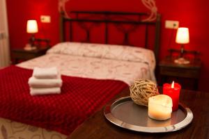 a red bedroom with a bed and a table with a candle at Apartamentos Las Palmeras in Cangas de Onís