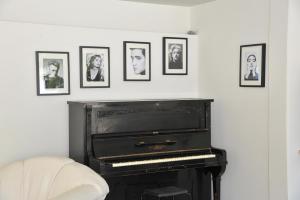 a piano in a living room with pictures on the wall at Pitsakis Hotel in Tolo