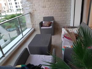 a balcony with two chairs and a table and a couch at Plage des Nations Prestigia Vue sur mer in Sidi Bouqnadel