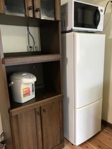 a kitchen with a refrigerator and a microwave at Guesthouse Matsushiro Walkers in Nagano