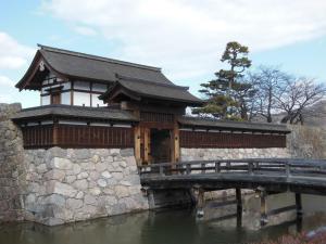 a building on a bridge over a body of water at Guesthouse Matsushiro Walkers in Nagano