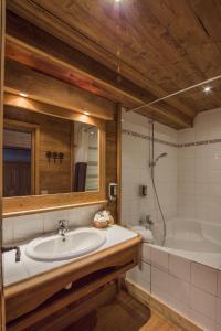 a bathroom with a sink and a tub and a mirror at Hôtel Le Samovar in Val dʼIsère