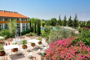 un patio esterno con tavoli, sedie e fiori di Parc Hotel a Peschiera del Garda