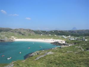 a beach with a group of boats in the water at North Coast 500 Pods in Achmelvich