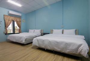 2 camas en una habitación con paredes azules en Ruisui Village Homestay, en Ruisui