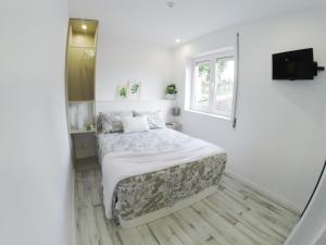 um quarto branco com uma cama e uma janela em Casa d'Avó no Porto