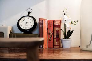 un groupe de livres et une horloge sur une table dans l'établissement Bel and The Dragon-Odiham, à Odiham