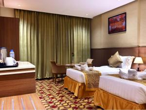 a hotel room with two beds and a table at Batoul Ajyad Hotel in Makkah