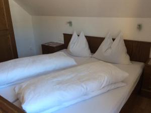 ein weißes Bett mit weißer Bettwäsche und Kissen darauf in der Unterkunft Apartment Gästehaus Wastian in Weissbriach