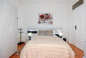a white bedroom with a bed and a bike painting at IN PORTO - Santa Catarina Apartment in Porto