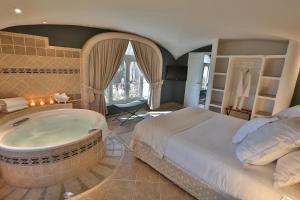 a bedroom with a large bed and a tub at Ostella Spa & Resort in Bastia