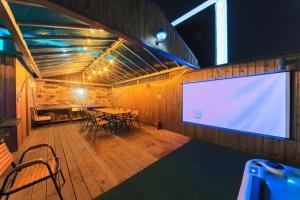 a large screen in a room with a table and chairs at Guwol Hotel in Incheon