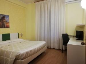 Dormitorio con cama, escritorio y TV en Albergo Roma, en Lanciano