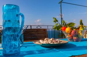 a blue table with a plate of food and a vase of fruit at Isabella Massalubrense in Massa Lubrense