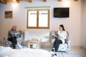 Dos mujeres sentadas en sillas en una habitación en Vila "Maglić", en Tjentište
