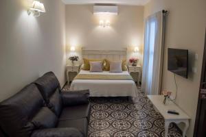 a hotel room with a bed and a couch at Hostal Boutique Casa La Laja in Chiclana de la Frontera