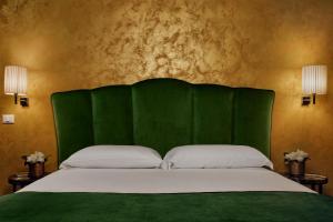 a bed with a green head board with two pillows at San Lio Tourist House in Venice