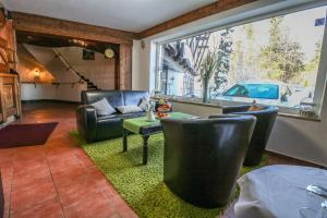 a living room with leather furniture and a large window at Hotel Quellenhof in Grainau