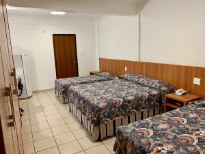 a hotel room with three beds and a door at Hotel Flat Alameda in Araçatuba