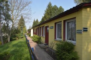 a yellow building with a sidewalk next to a yard at Ferienanlage Reinsberger Dorf in Plaue