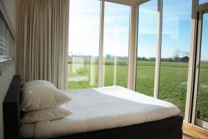 Bett in einem Zimmer mit einem großen Fenster in der Unterkunft Hotel & Restaurant Weidumerhout in Weidum