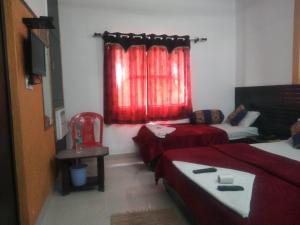 Habitación con 2 camas y ventana con cortinas rojas. en Hotel Grace en Agra