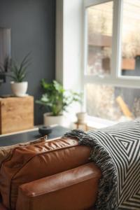 a brown leather couch in a living room with a window at Lokal Hotel Fishtown in Philadelphia