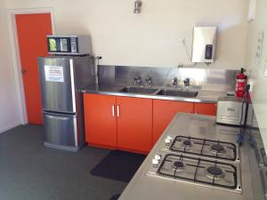a kitchen with orange cabinets and a stainless steel refrigerator at Picton Campervan Park in Picton