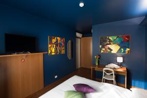 um quarto com paredes azuis, uma cama e uma secretária em Albergo Residenza Al Teatro em Udine